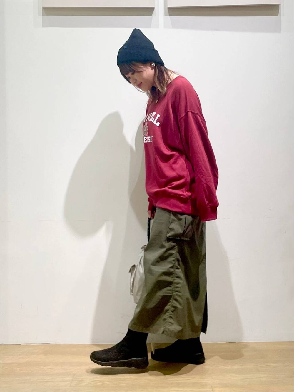 グリーン系のスカート、グレー系のショルダーバッグ、ブラック系のブーツを着用したレディースの秋コーディネートの2枚目の写真