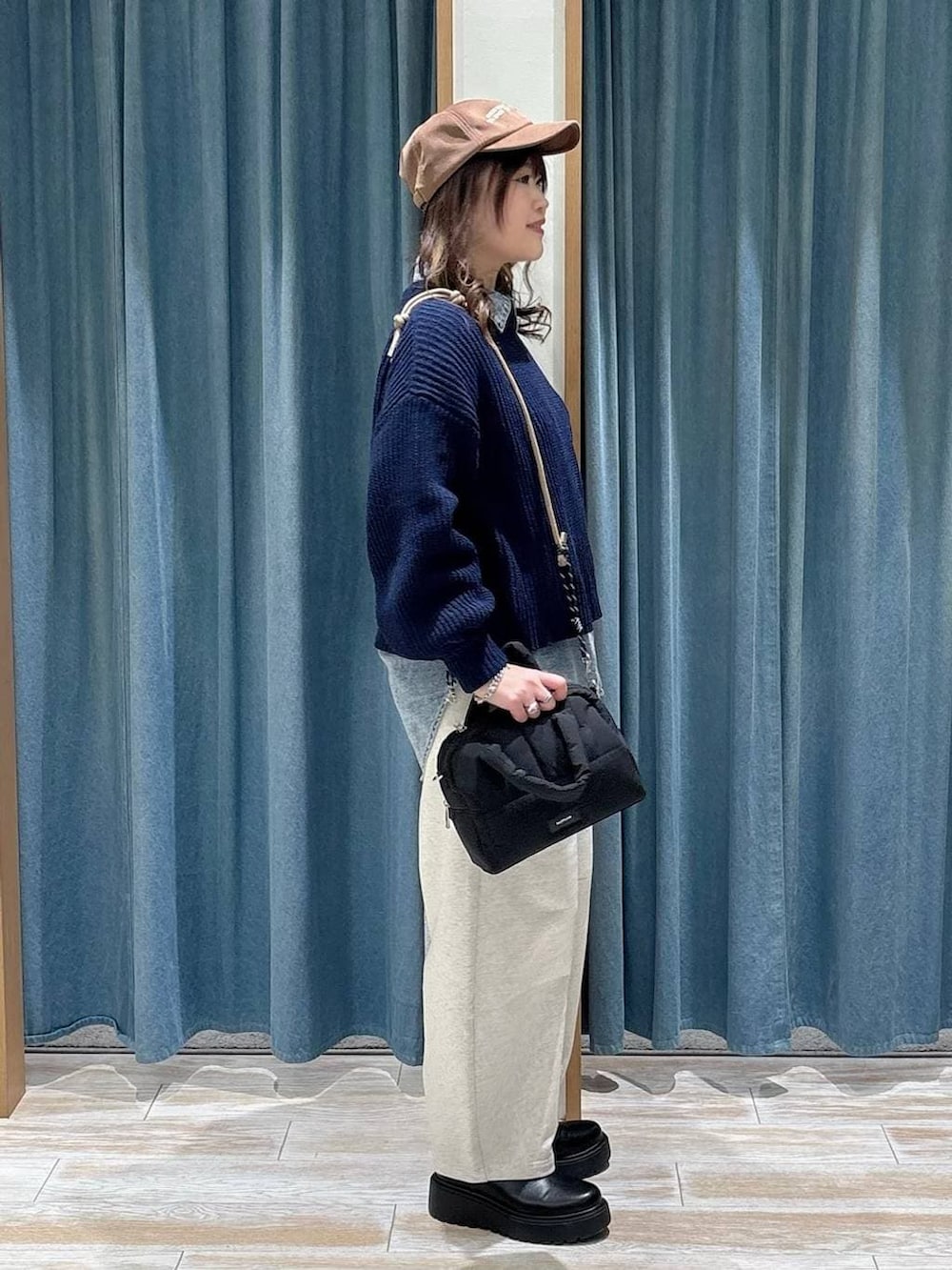ブラック系のブーツ、ブラック系のボストンバッグ、ブルー系のニット/セーターを着用したレディースの冬コーディネートの2枚目の写真