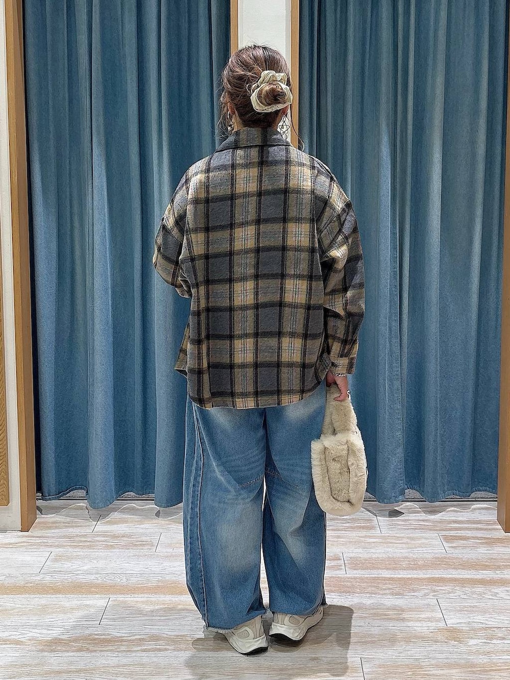 ブルー系のデニムパンツ、ベージュ系のトートバッグ、ホワイト系のスニーカーを着用したレディースの秋コーディネートの3枚目の写真
