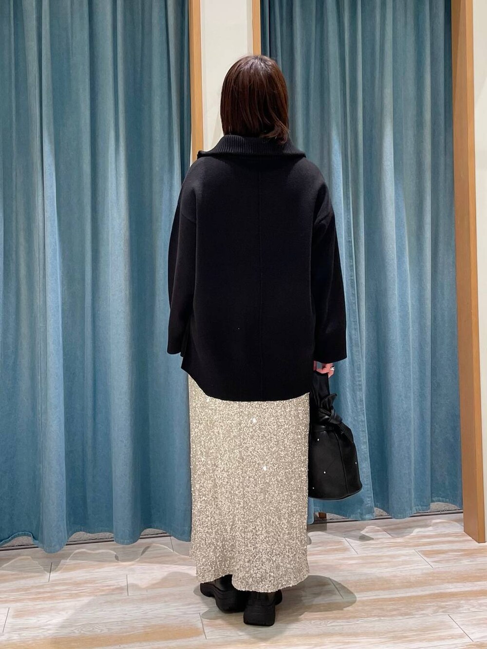 ブラック系のブーツ、ブラック系のニット/セーター、ブラック系のショルダーバッグを着用したレディースの冬コーディネートの2枚目の写真