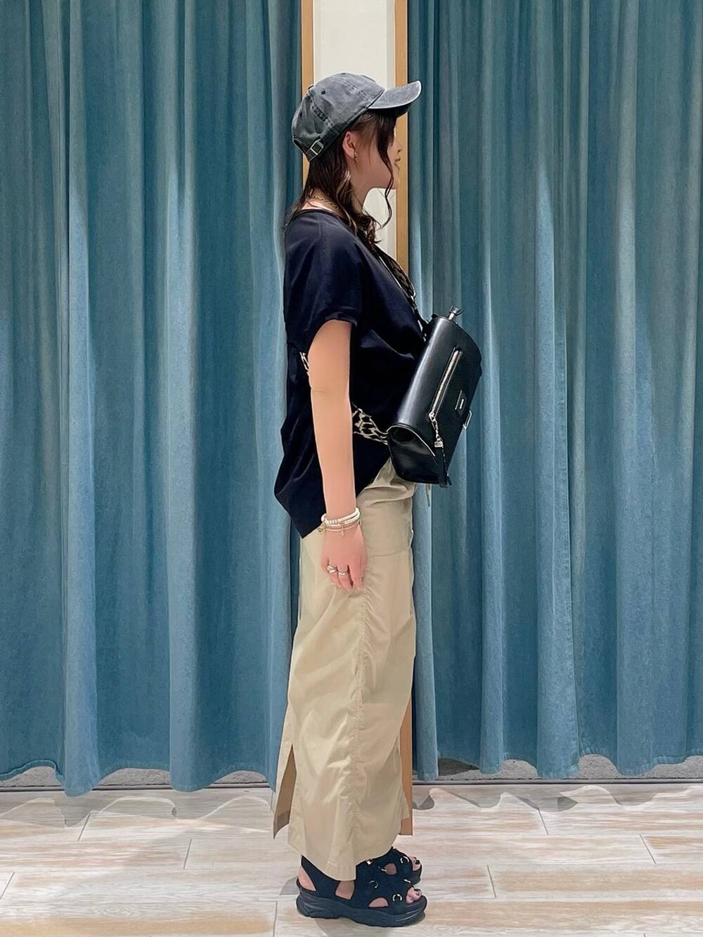 ブラック系のTシャツ/カットソー、ベージュ系のスカート、ブラック系のサンダルを着用したレディースの春コーディネートの2枚目の写真