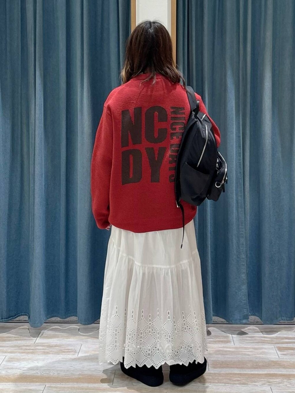 ブラック系のブーツ、ブラック系のバックパック/リュック、ホワイト系のスカートを着用したレディースの秋コーディネートの3枚目の写真