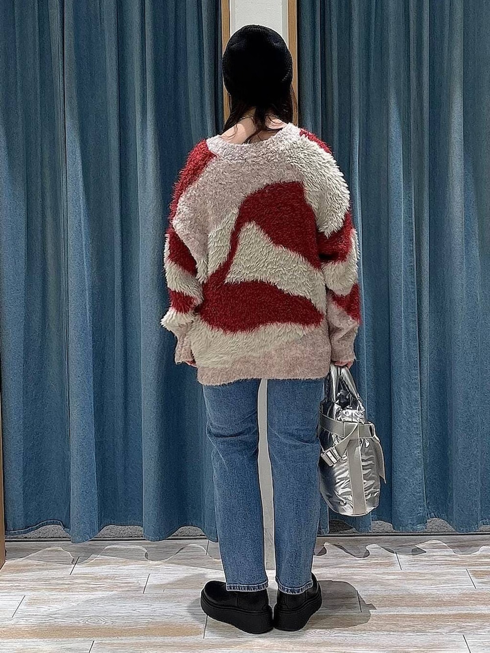 シルバー系のトートバッグ、ブラック系のブーツ、レッド系のカーディガン/ボレロを着用したレディースの冬コーディネートの3枚目の写真