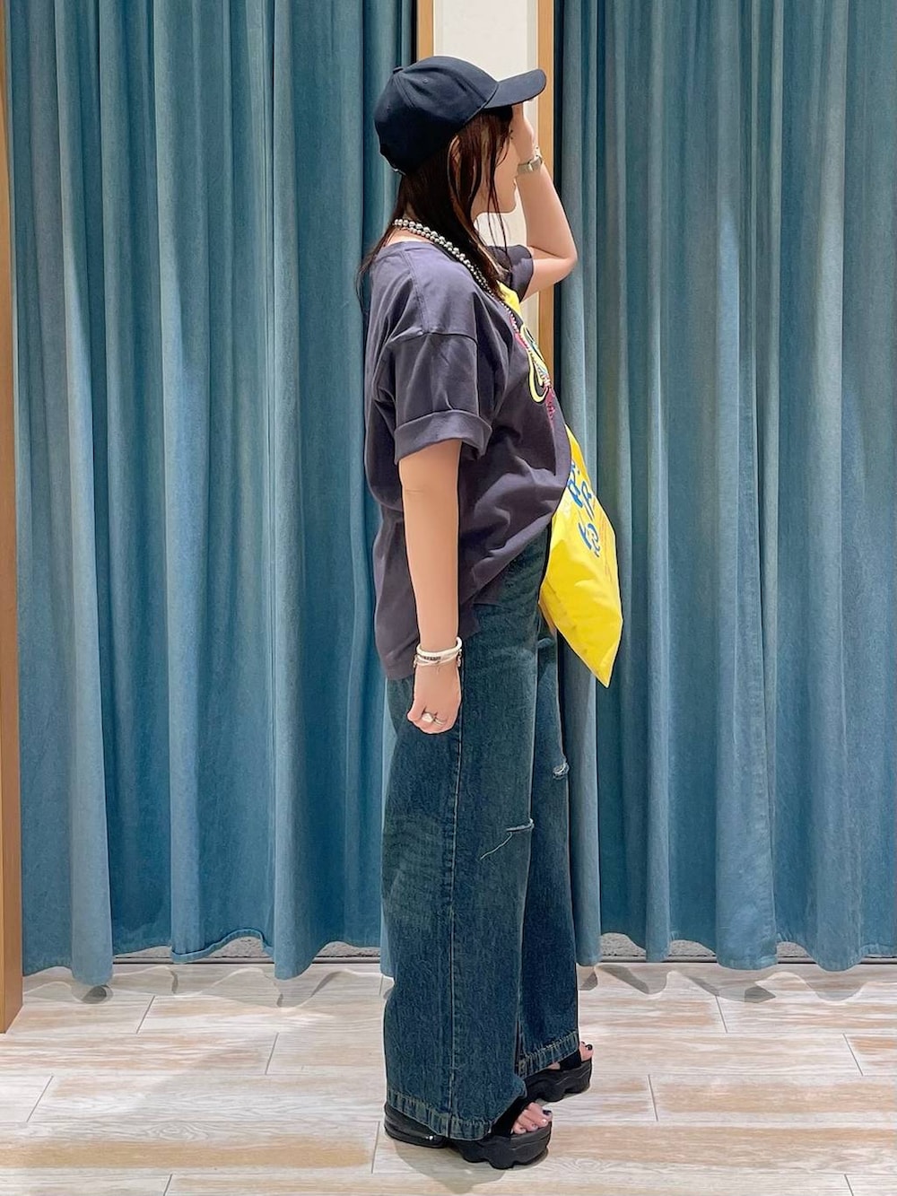 ブルー系のデニムパンツ、イエロー系のトートバッグ、グレー系のTシャツ/カットソーを着用したレディースの夏コーディネートの2枚目の写真