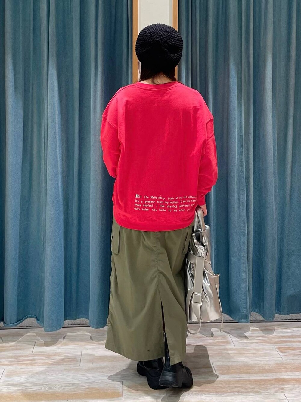 グリーン系のスカート、ブラック系のブーツ、シルバー系のトートバッグを着用したレディースの冬コーディネートの3枚目の写真