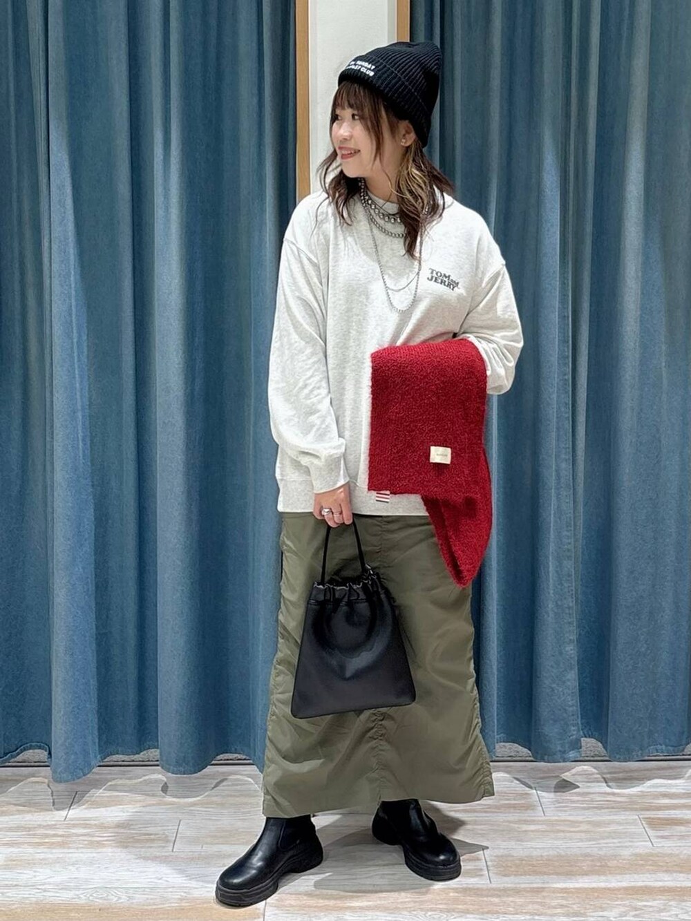 ブラック系のブーツ、グリーン系のスカート、ブラック系のハンドバッグを着用したレディースの秋コーディネートの2枚目の写真