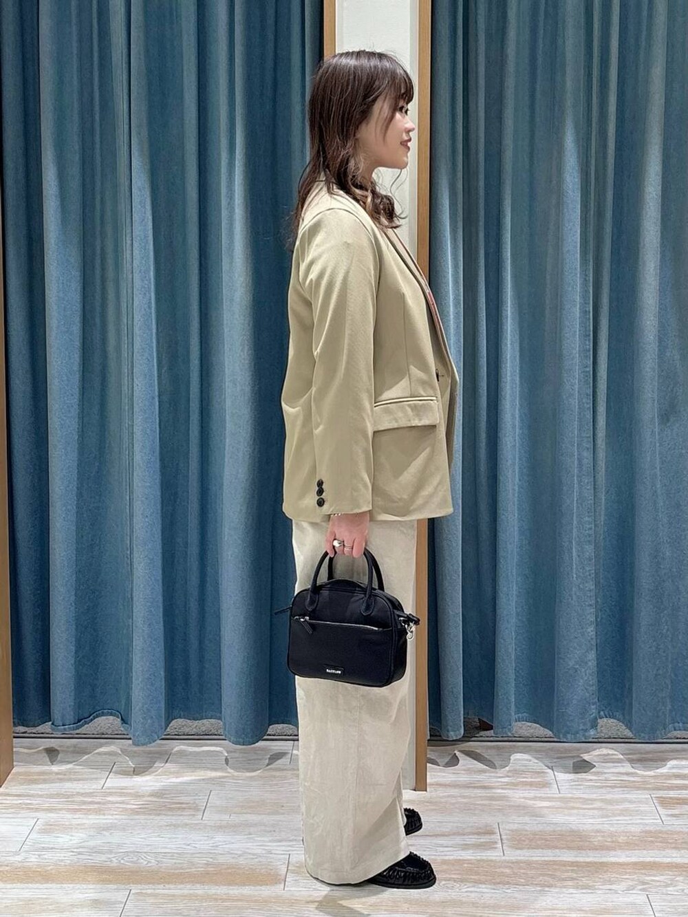 ブラック系のハンドバッグ、ブラック系のローファー、ベージュ系のテーラードジャケットを着用したレディースの冬コーディネートの2枚目の写真