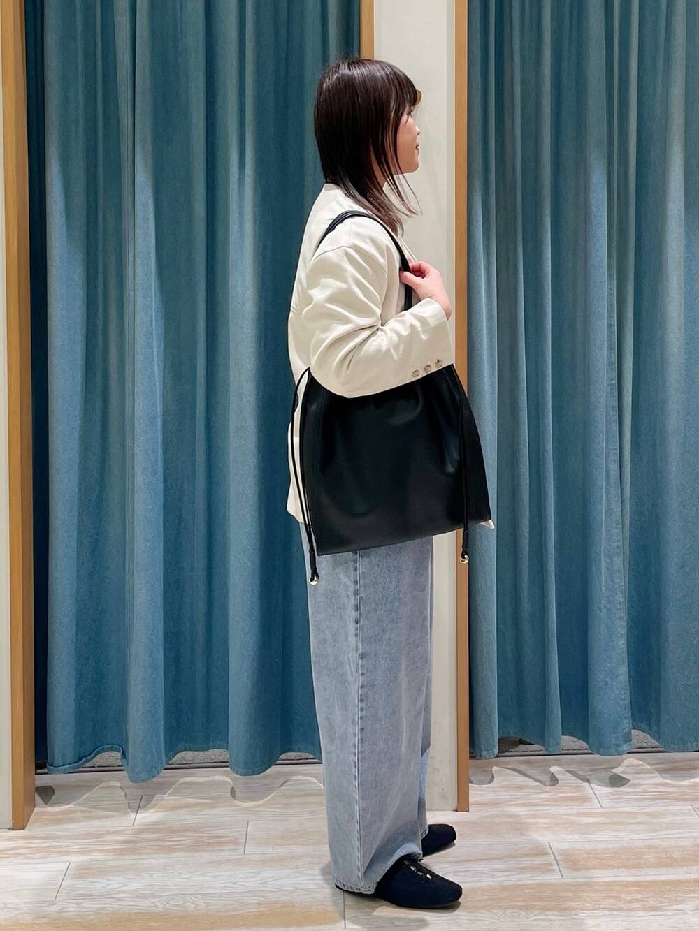 ブルー系のデニムパンツ、ホワイト系のTシャツ/カットソー、ブラック系のトートバッグを着用したレディースの春コーディネートの2枚目の写真