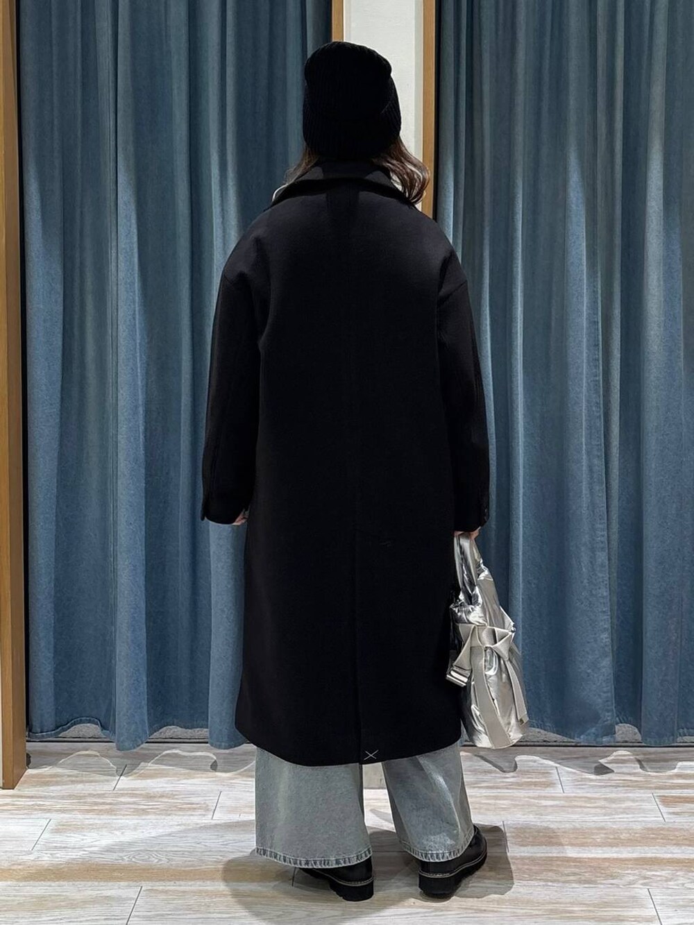 シルバー系のトートバッグ、ブラック系のチェスターコート、ブラック系のローファーを着用したレディースの秋コーディネートの3枚目の写真