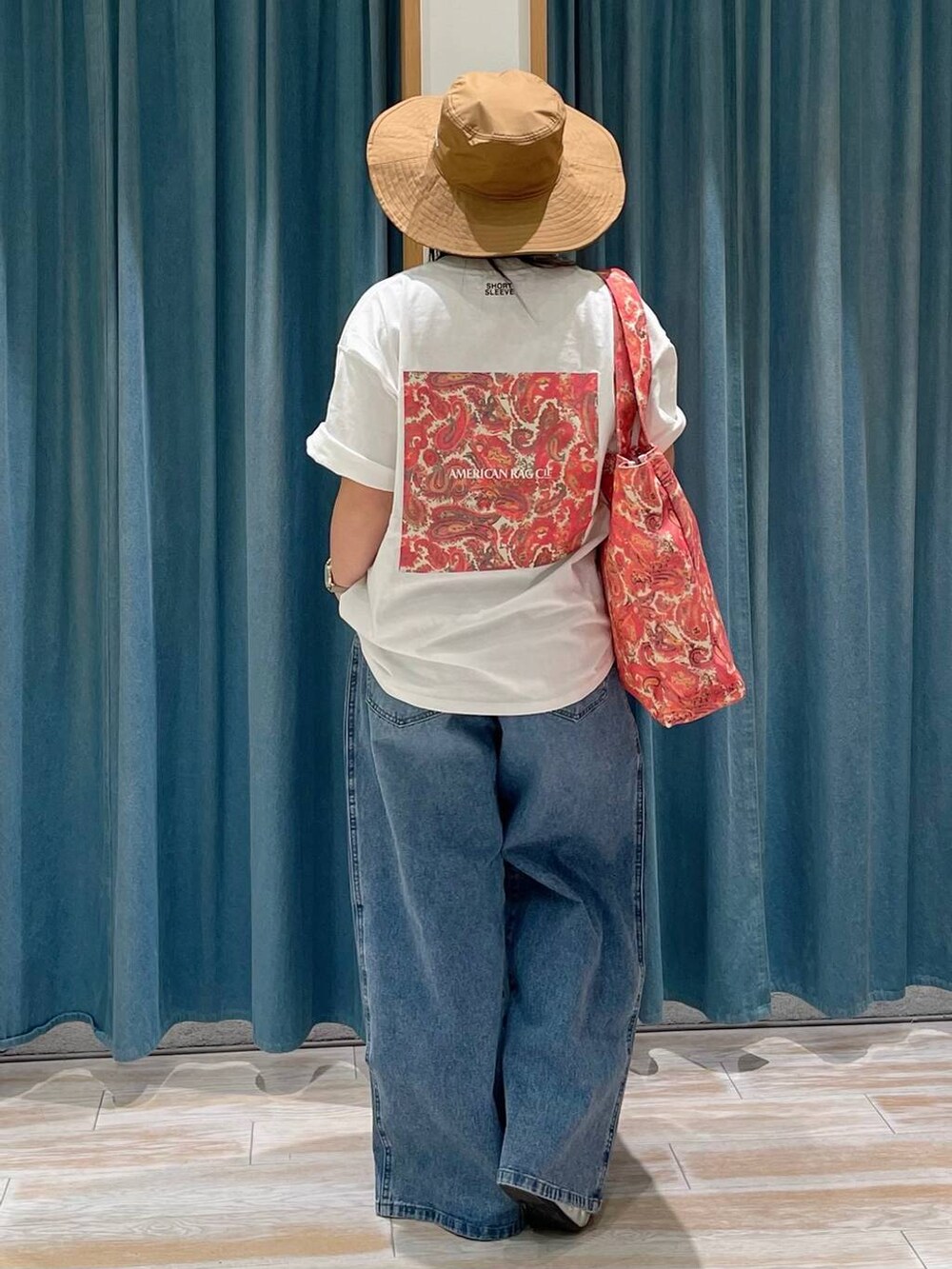 ブルー系のデニムパンツ、ホワイト系のTシャツ/カットソー、レッド系のトートバッグを着用したレディースの春コーディネートの3枚目の写真