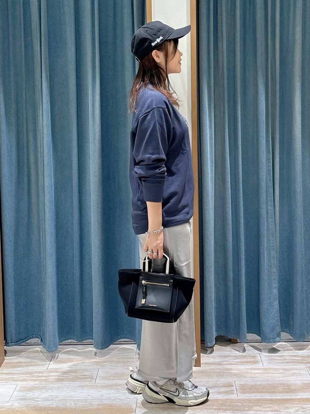 ブルー系のスウェット、ブラック系のショルダーバッグ、グレー系のスカートを着用したレディースの秋コーディネートの2枚目の写真