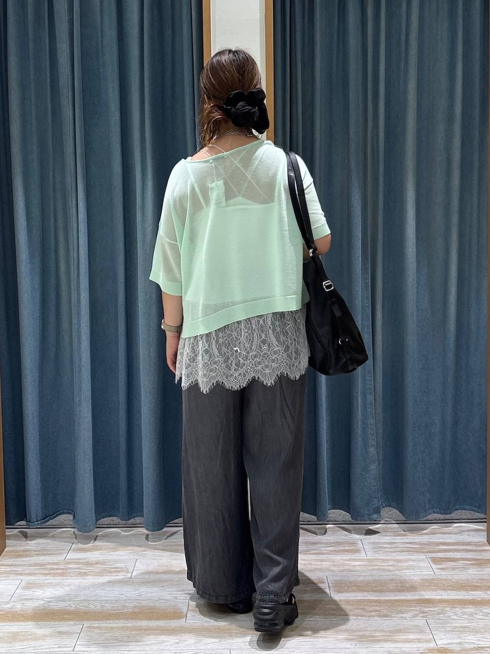 グリーン系のニット/セーター、ブラック系のトートバッグ、ブラック系のデニムパンツを着用したレディースの夏コーディネートの3枚目の写真