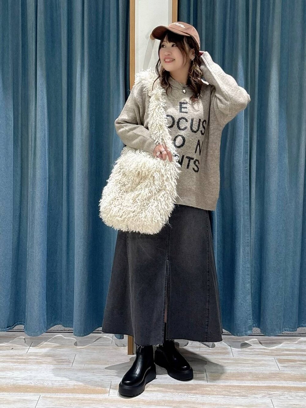 ブラック系のブーツ、ベージュ系のショルダーバッグ、ブラック系のスカートを着用したレディースの秋コーディネートの4枚目の写真