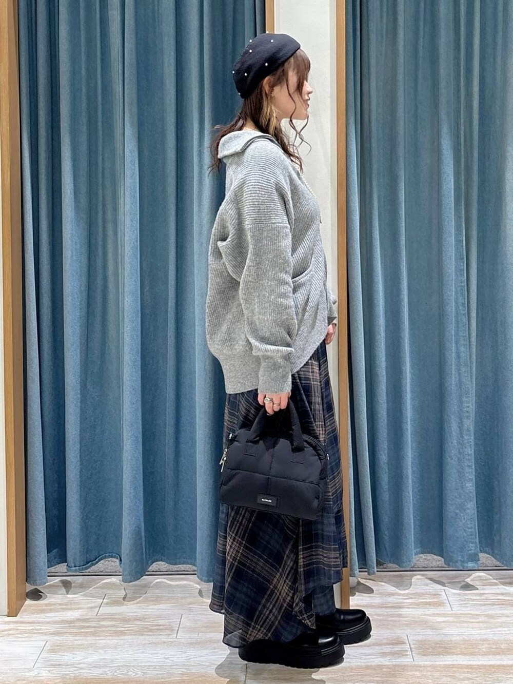 ブラック系のブーツ、ブラック系のボストンバッグ、グレー系のニット/セーターを着用したレディースの秋コーディネートの2枚目の写真