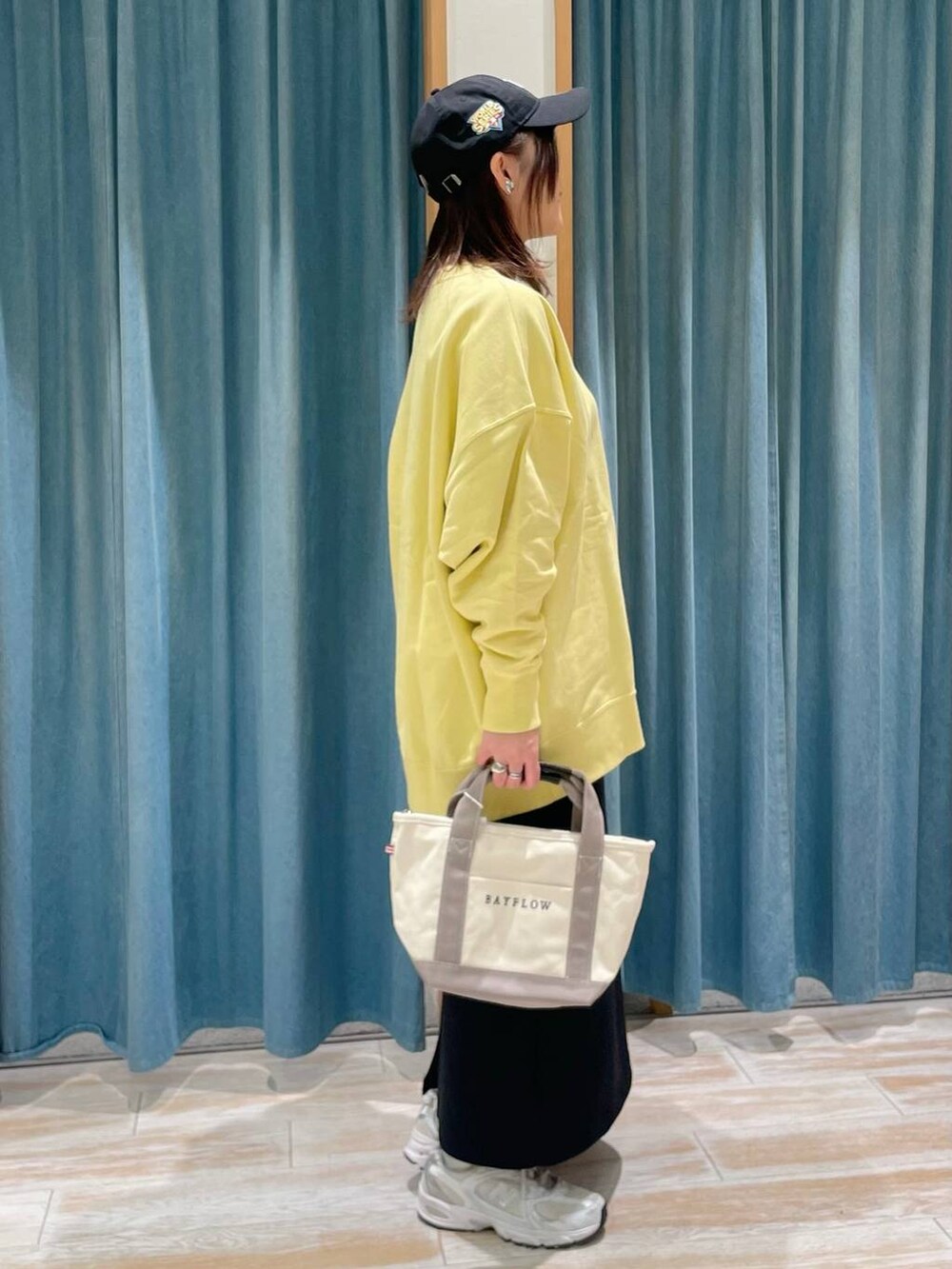 イエロー系のスウェット、ブラック系のスカート、グレー系のトートバッグを着用したレディースの冬コーディネートの2枚目の写真