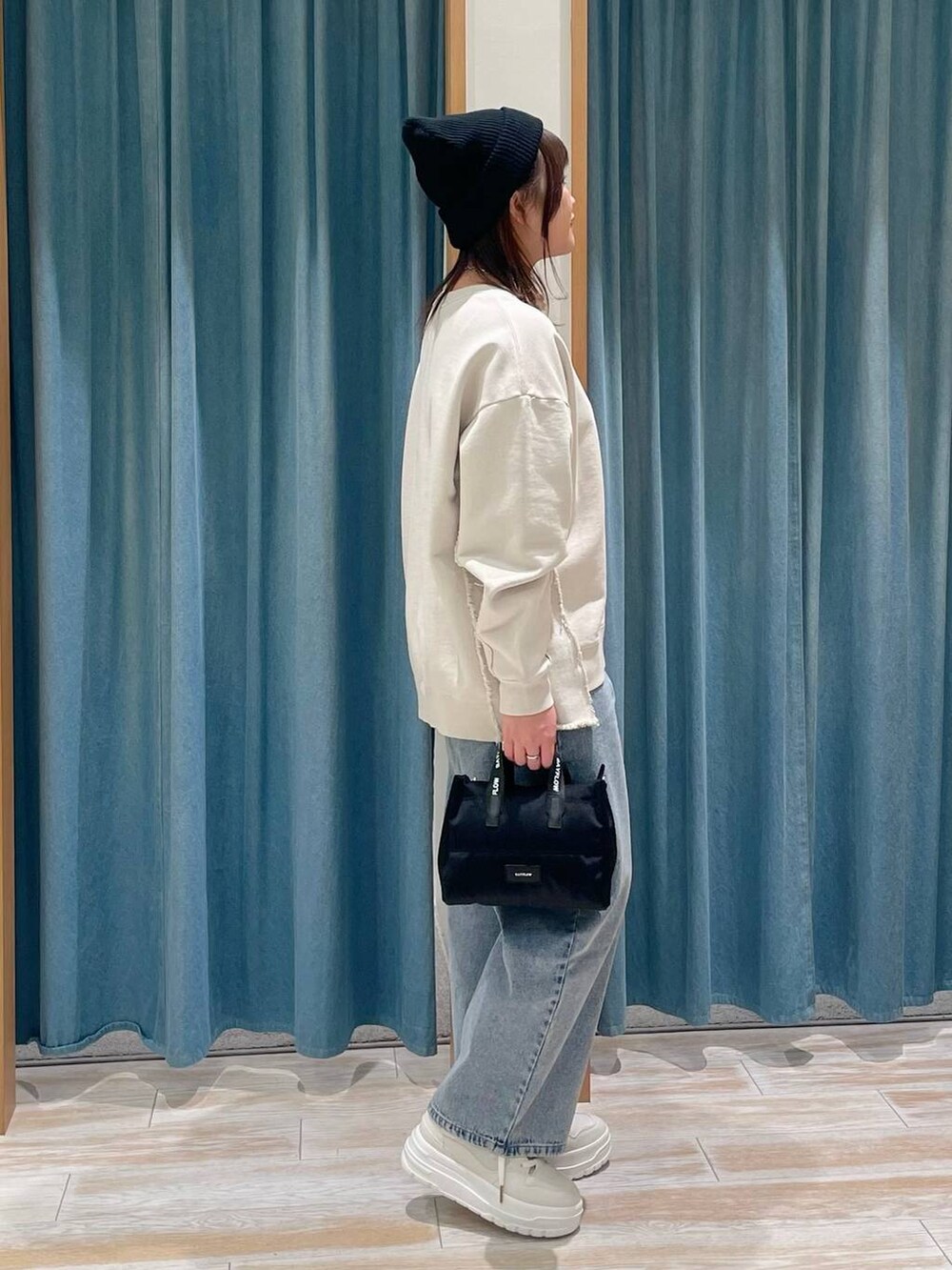 ホワイト系のスニーカー、ブルー系のデニムパンツ、ブラック系のショルダーバッグを着用したレディースの冬コーディネートの2枚目の写真