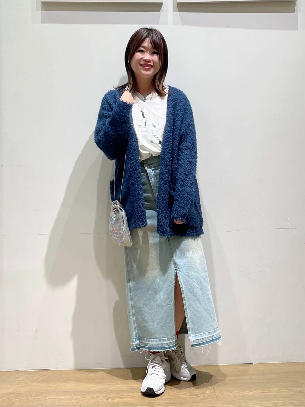 ブルー系のデニムスカート、ホワイト系のTシャツ/カットソー、ブルー系のカーディガン/ボレロを着用したレディースの秋コーディネートの2枚目の写真