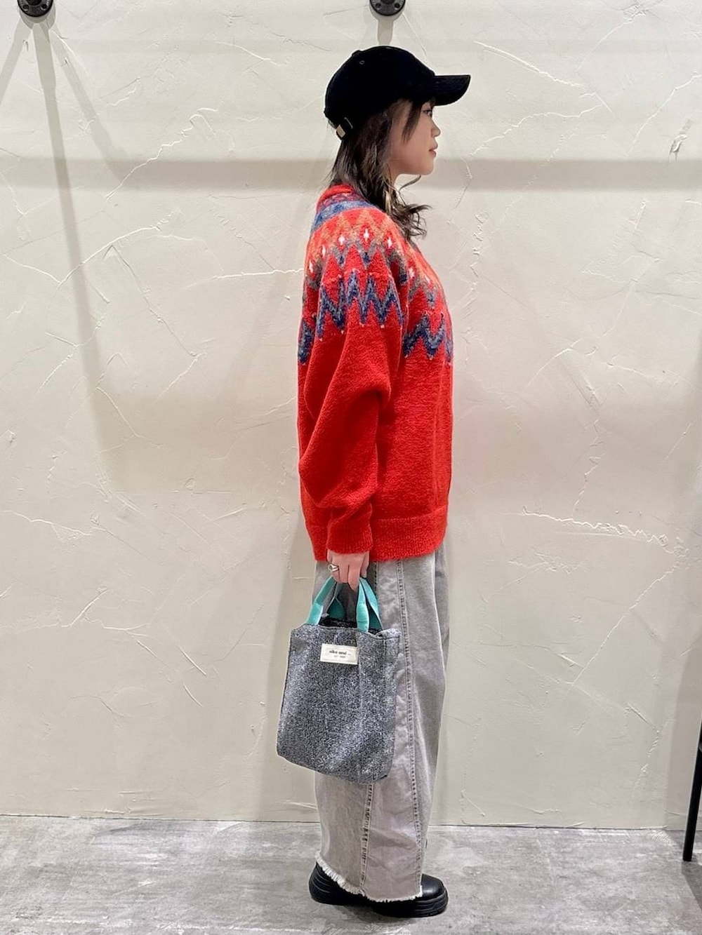 グレー系のデニムパンツ、シルバー系のトートバッグ、レッド系のニット/セーターを着用したレディースの冬コーディネートの2枚目の写真