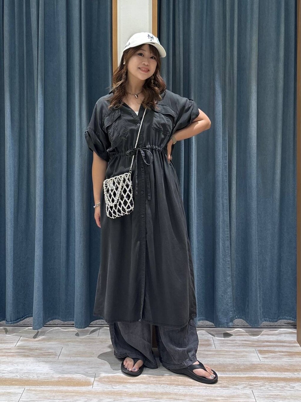 シルバー系のショルダーバッグ、ブラック系のデニムパンツ、ブラック系のサンダルを着用したレディースの夏コーディネートの4枚目の写真