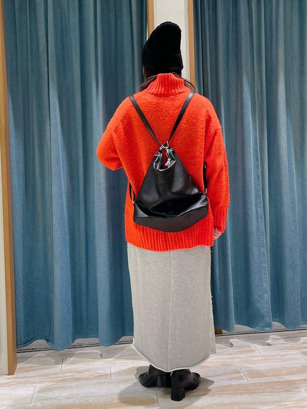 ブラック系のブーツ、ブラック系のショルダーバッグ、オレンジ系のニット/セーターを着用したレディースの冬コーディネートの3枚目の写真