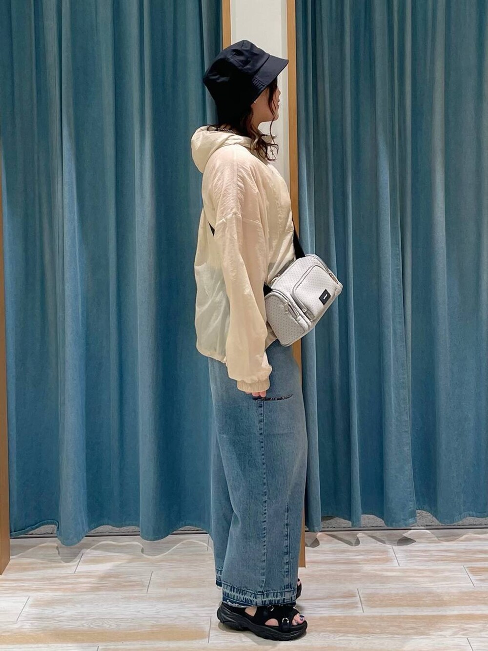 ホワイト系のキャミソール、ブルー系のデニムパンツ、ブラック系のサンダルを着用したレディースの春コーディネートの2枚目の写真