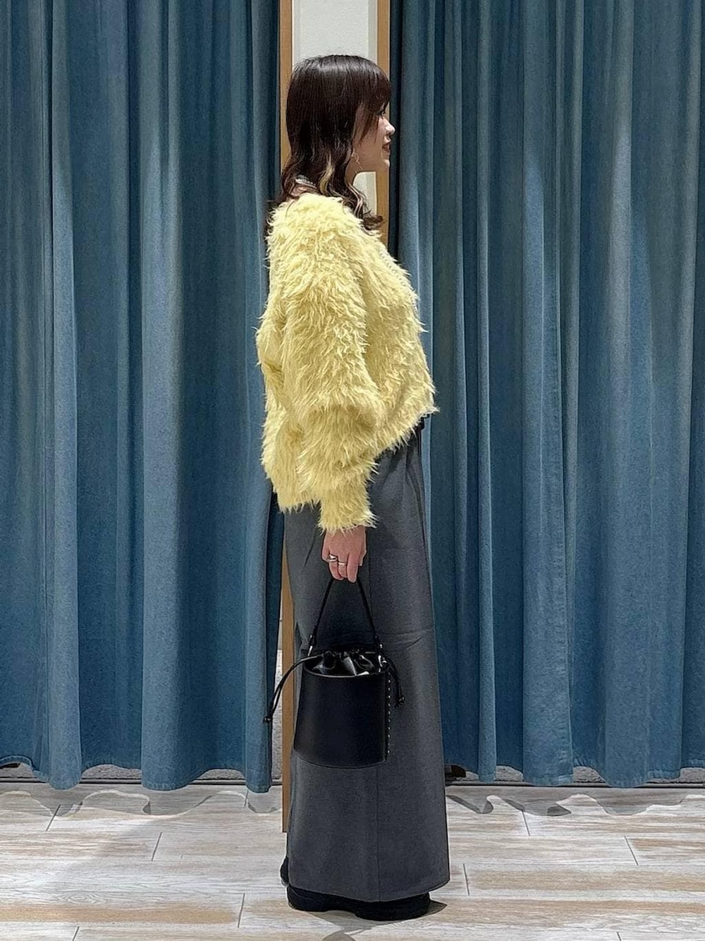 グレー系のその他パンツ、イエロー系のカーディガン/ボレロ、ブラック系のハンドバッグを着用したレディースの冬コーディネートの2枚目の写真