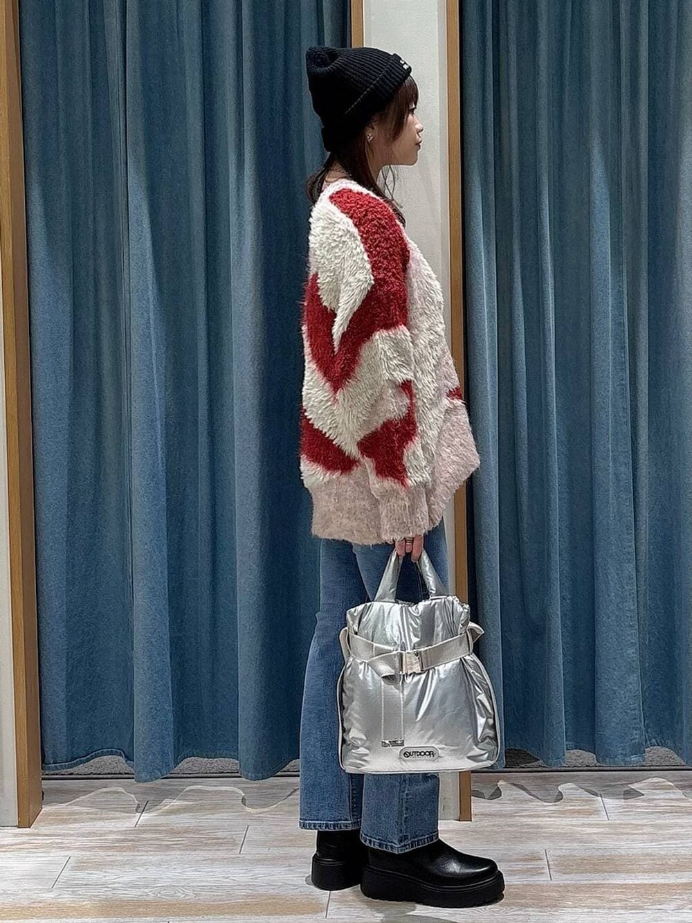 シルバー系のトートバッグ、ブラック系のブーツ、レッド系のカーディガン/ボレロを着用したレディースの冬コーディネートの2枚目の写真