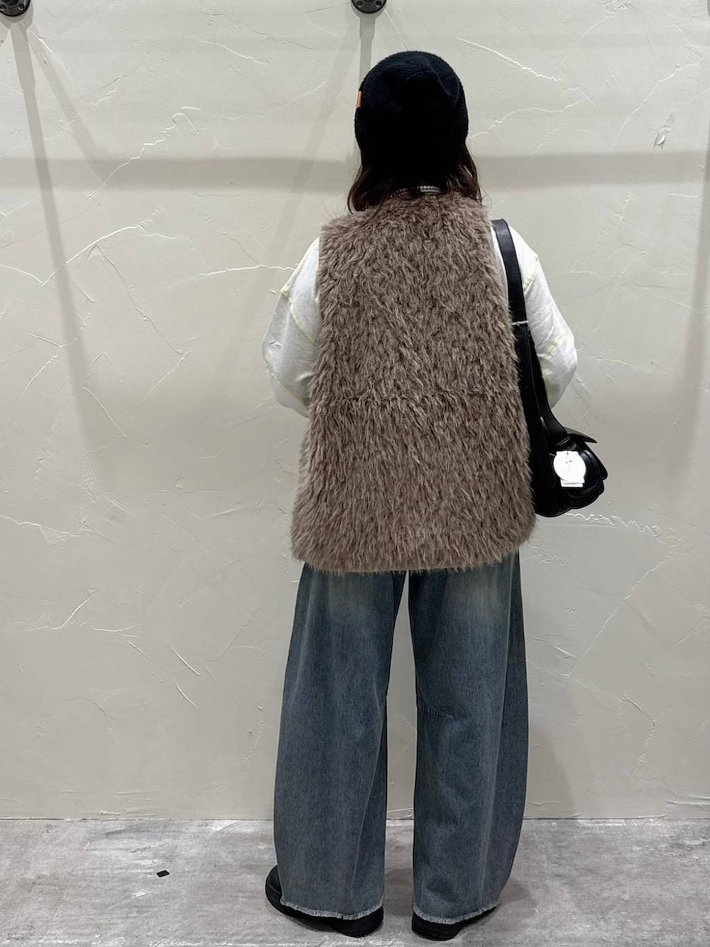 ベージュ系のベスト、ブルー系のデニムパンツ、ブラック系のショルダーバッグを着用したレディースの秋コーディネートの3枚目の写真