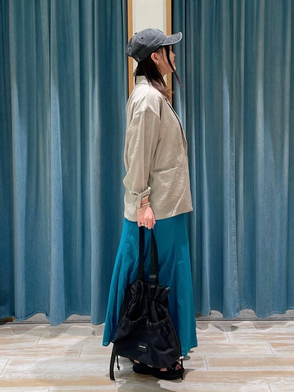 ホワイト系のキャミソール、ブラック系のトートバッグ、ブルー系のスカートを着用したレディースの春コーディネートの2枚目の写真