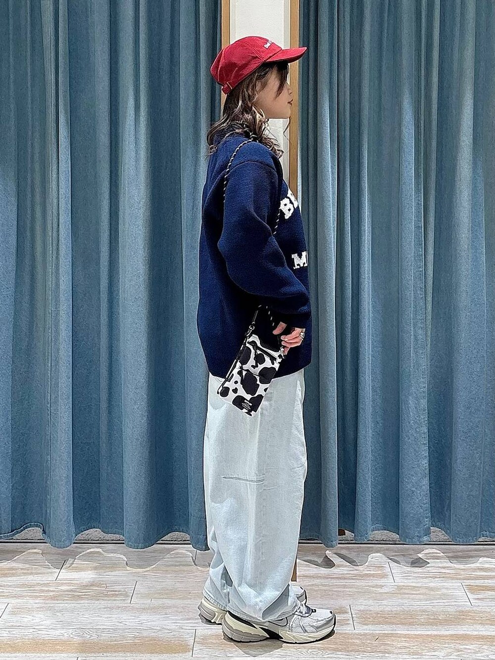 ブルー系のニット/セーター、ブルー系のデニムパンツ、レッド系のキャップを着用したレディースの冬コーディネートの2枚目の写真