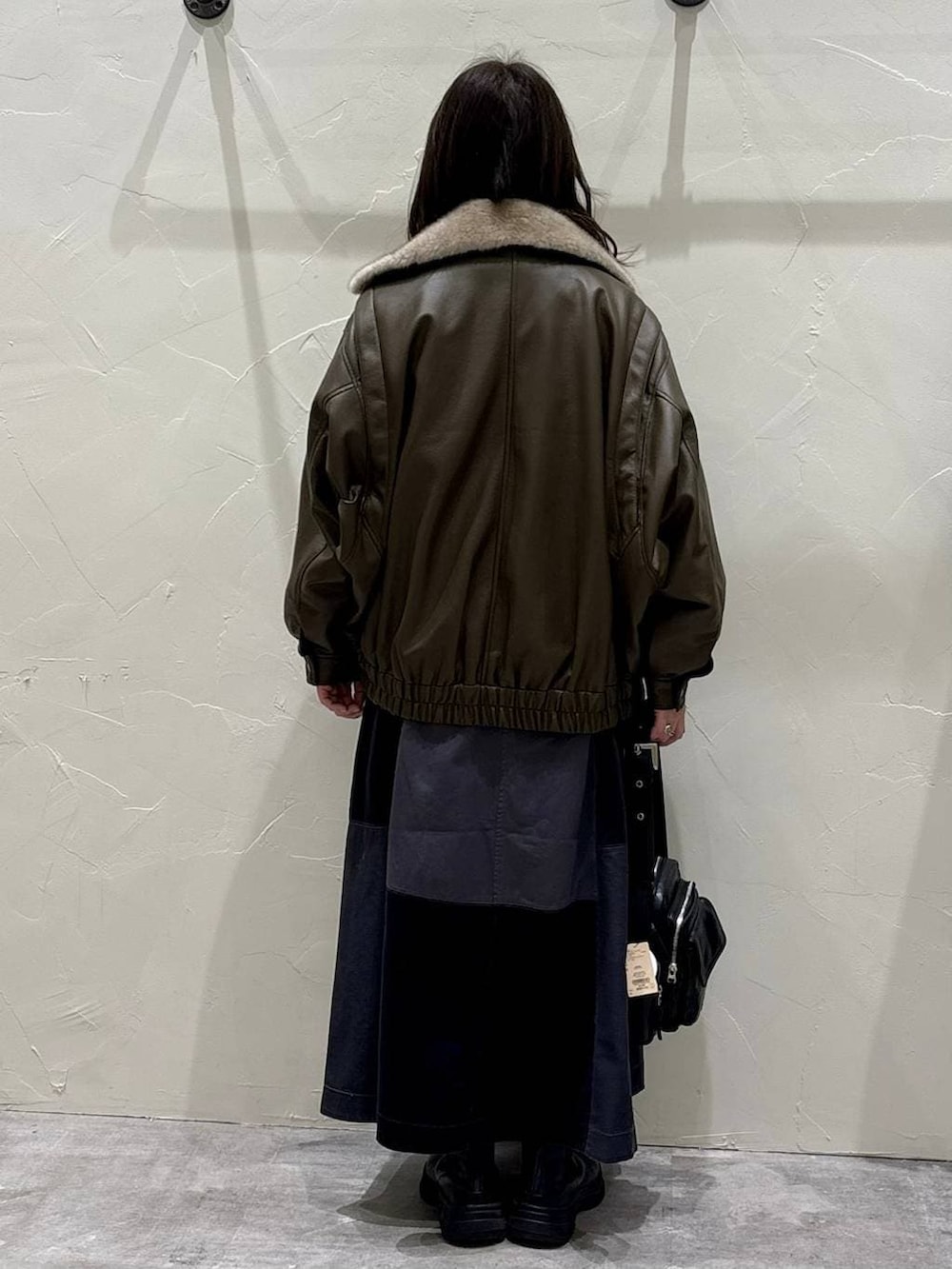 グレー系のスカート、ブラウン系のブルゾン、ブラック系のブーツを着用したレディースの冬コーディネートの3枚目の写真