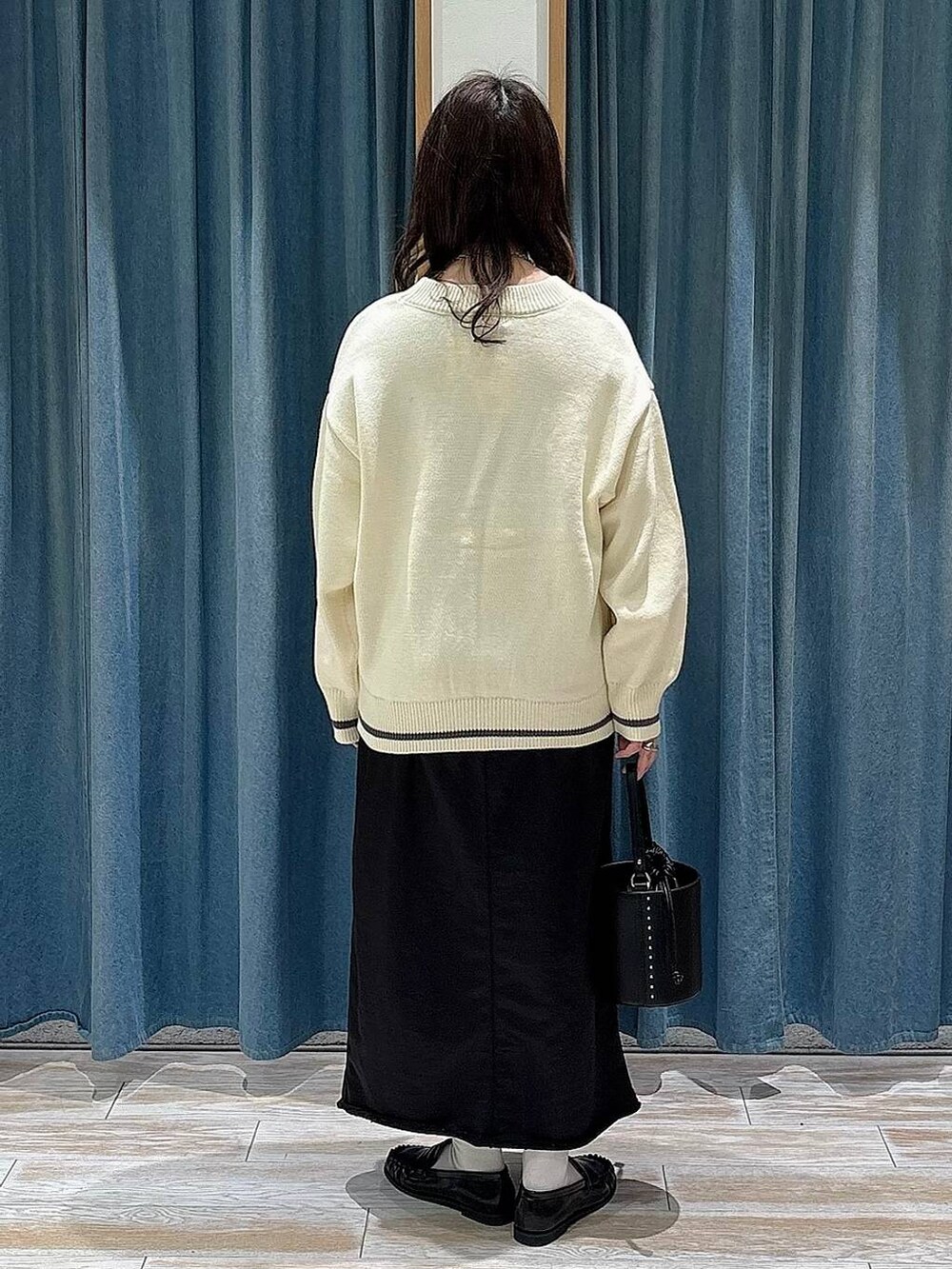 ブラック系のスカート、ホワイト系のカーディガン/ボレロ、ブラック系のハンドバッグを着用したレディースの冬コーディネートの3枚目の写真