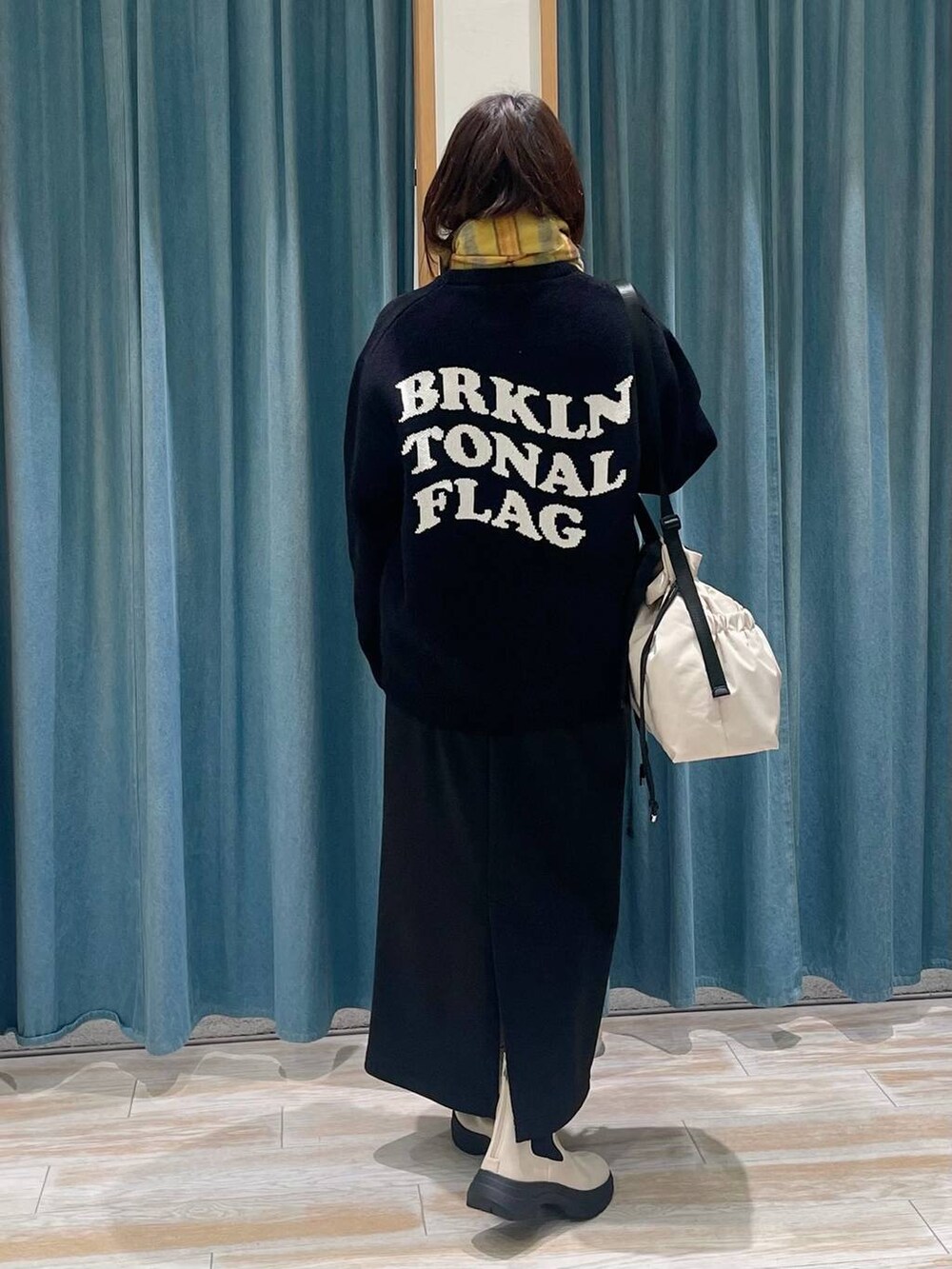 ホワイト系のブーツ、ブラック系のニット/セーター、ホワイト系のトートバッグを着用したレディースの冬コーディネートの2枚目の写真