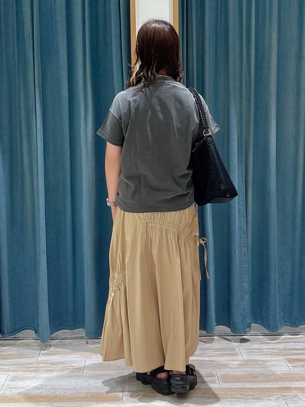 グレー系のTシャツ/カットソー、ブラック系のハンドバッグ、イエロー系のスカートを着用したレディースの夏コーディネートの3枚目の写真