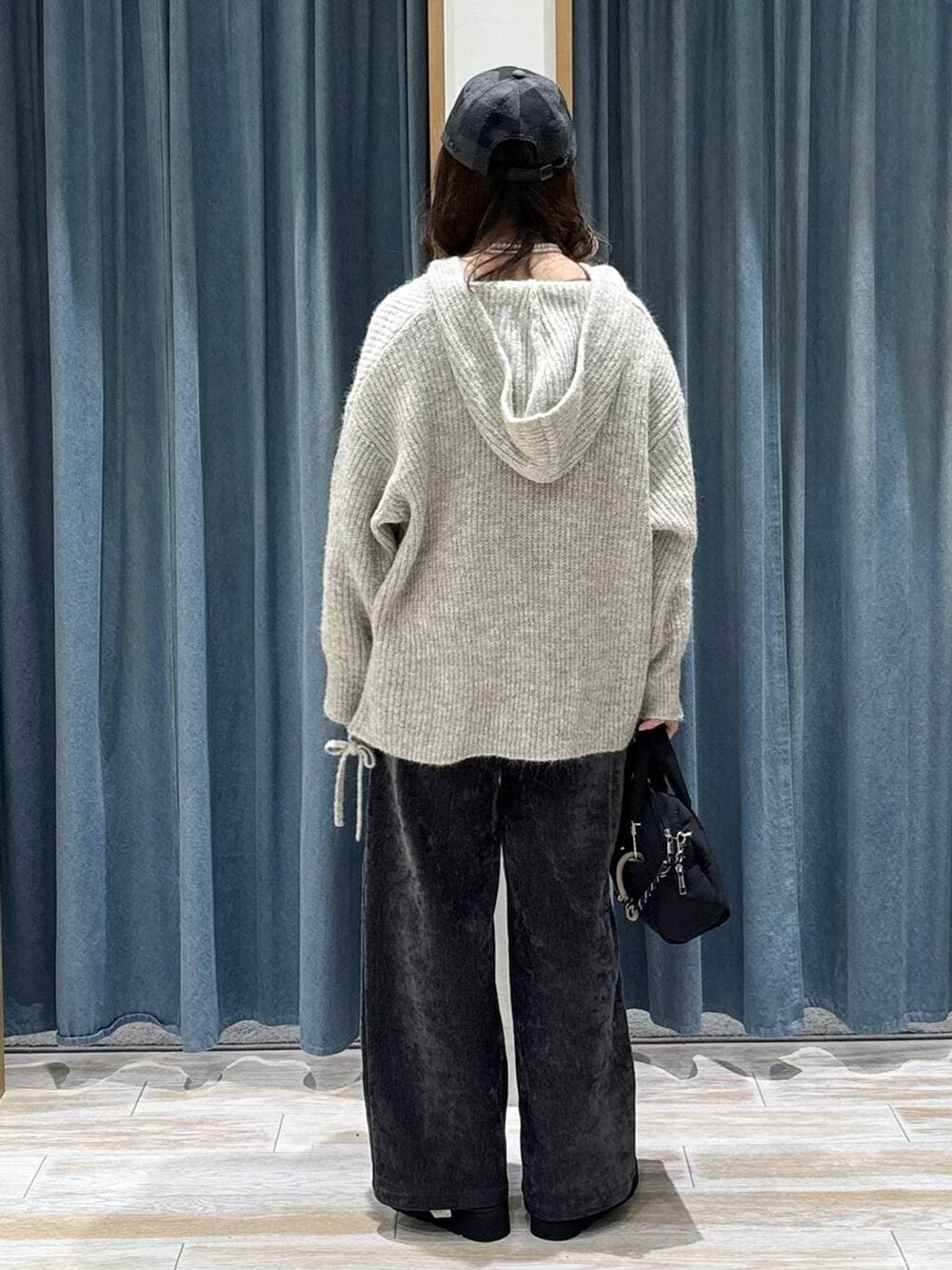 ブラック系のボストンバッグ、ベージュ系のブーツ、グレー系のその他パンツを着用したレディースの秋コーディネートの3枚目の写真