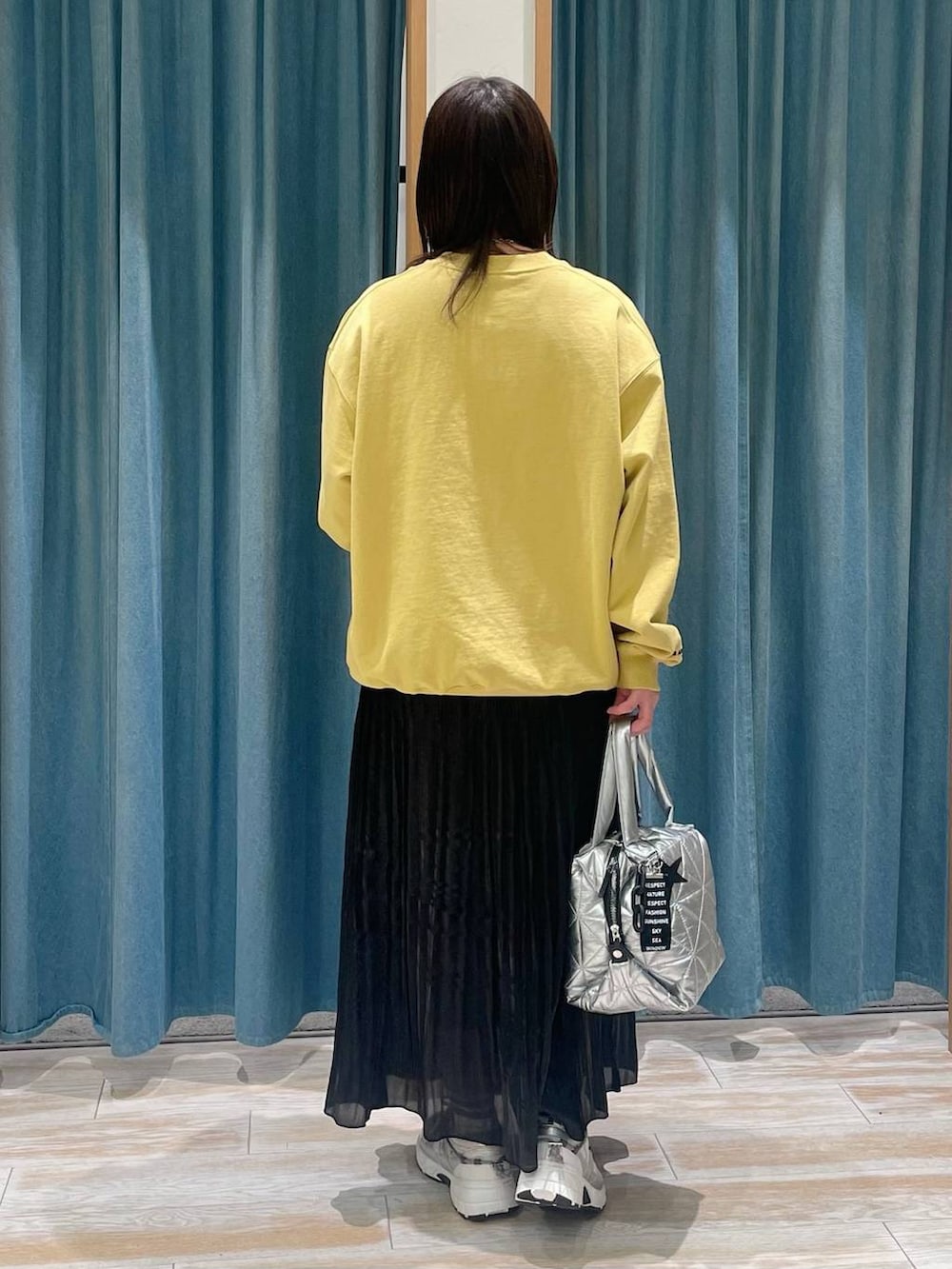 ホワイト系のスニーカー、ブラック系のスカート、シルバー系のトートバッグを着用したレディースの冬コーディネートの2枚目の写真