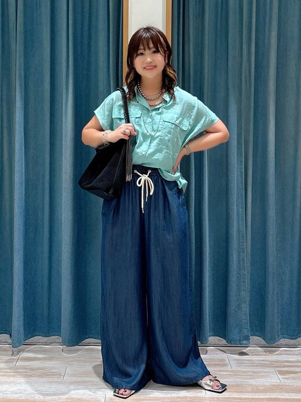 グリーン系のシャツ/ブラウス、シルバー系のサンダル、ブラック系のハンドバッグを着用したレディースの夏コーディネートの4枚目の写真