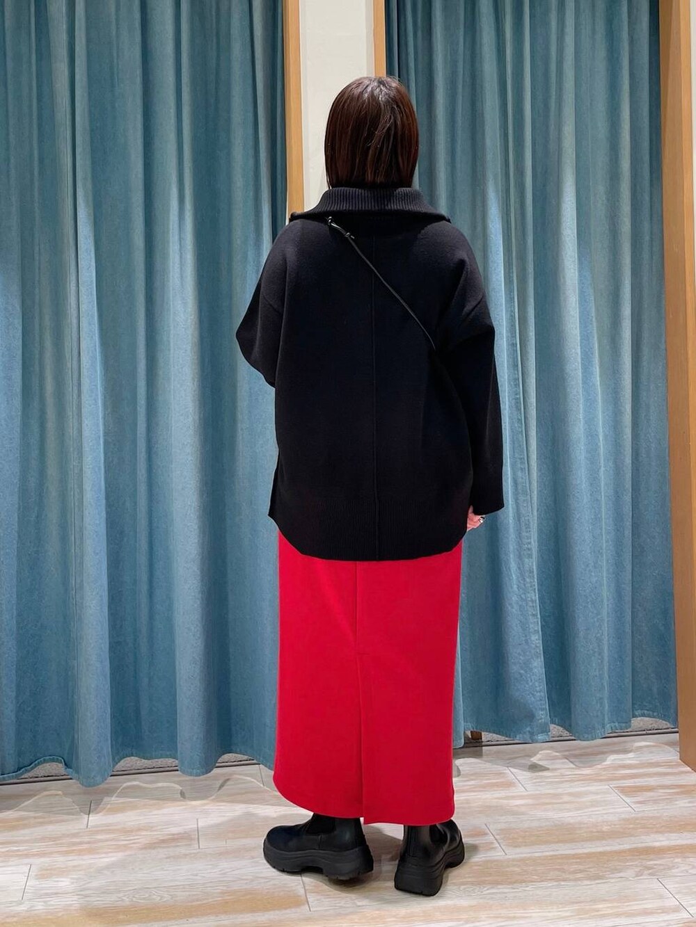 グレー系のショルダーバッグ、ブラック系のブーツ、ブラック系のニット/セーターを着用したレディースの冬コーディネートの2枚目の写真