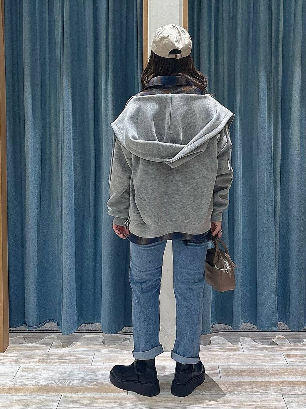 ブラック系のブーツ、ブラウン系のハンドバッグ、ブルー系のデニムパンツを着用したレディースの冬コーディネートの3枚目の写真