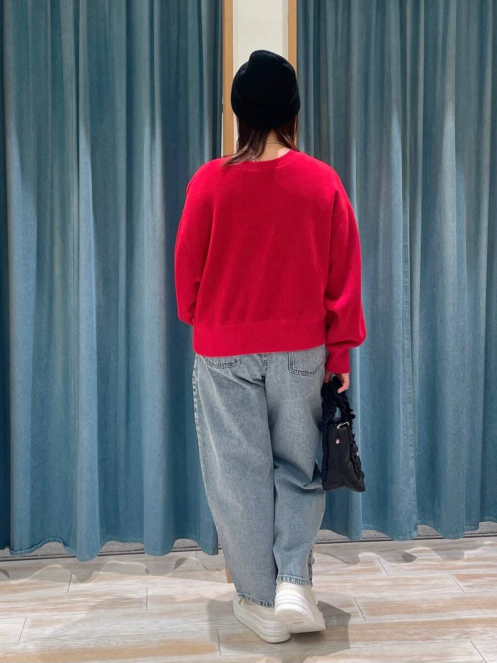 ホワイト系のスニーカー、ブラック系のトートバッグ、ブルー系のデニムパンツを着用したレディースの冬コーディネートの3枚目の写真