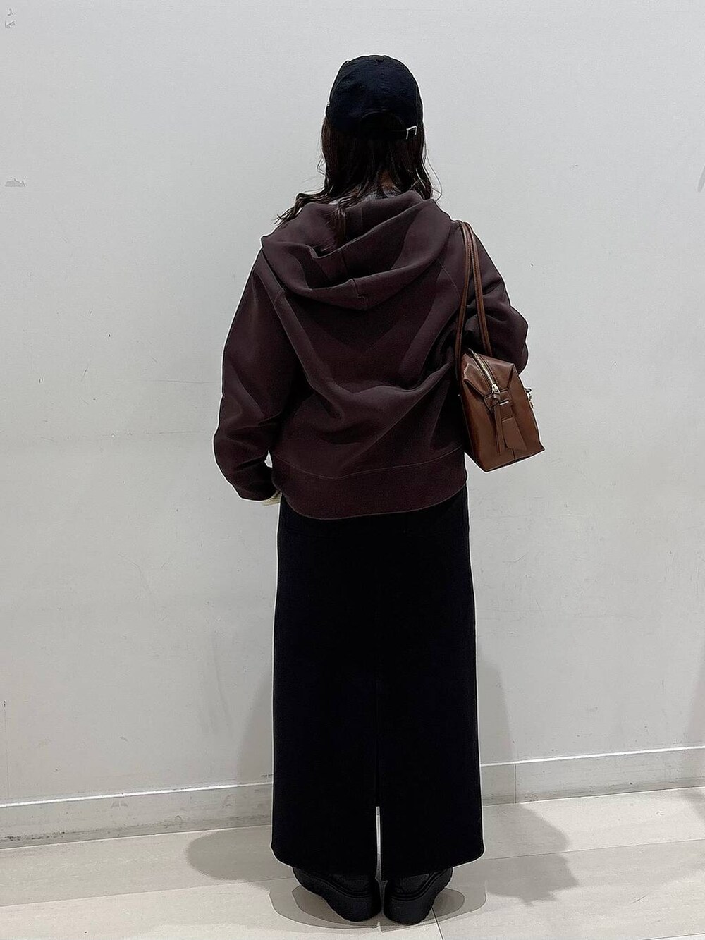 ブラウン系のボストンバッグ、ブラック系のブーツ、ブラウン系のパーカーを着用したレディースの冬コーディネートの3枚目の写真