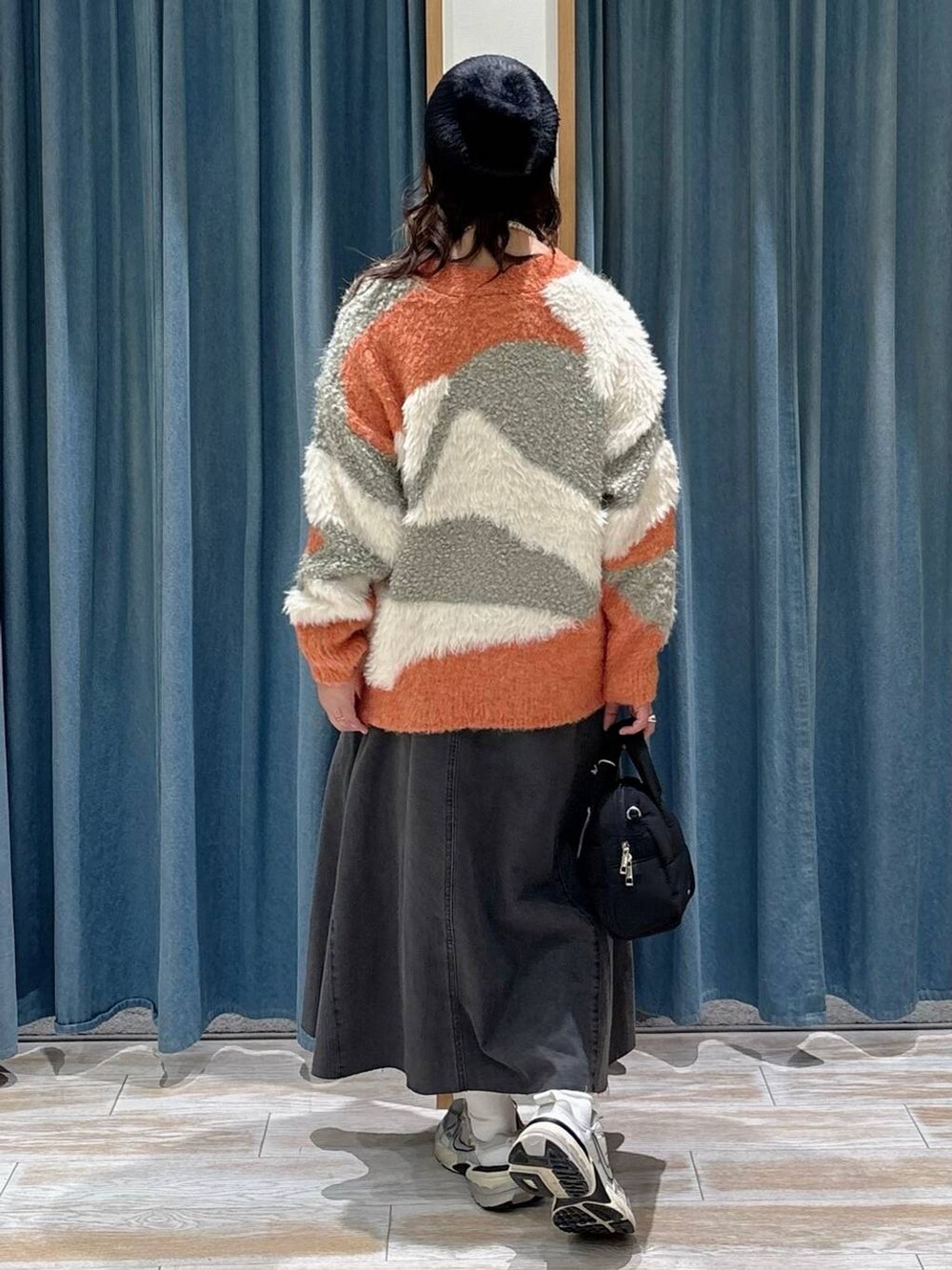 オレンジ系のカーディガン/ボレロ、ブラック系のスカート、ブラック系のボストンバッグを着用したレディースの秋コーディネートの3枚目の写真