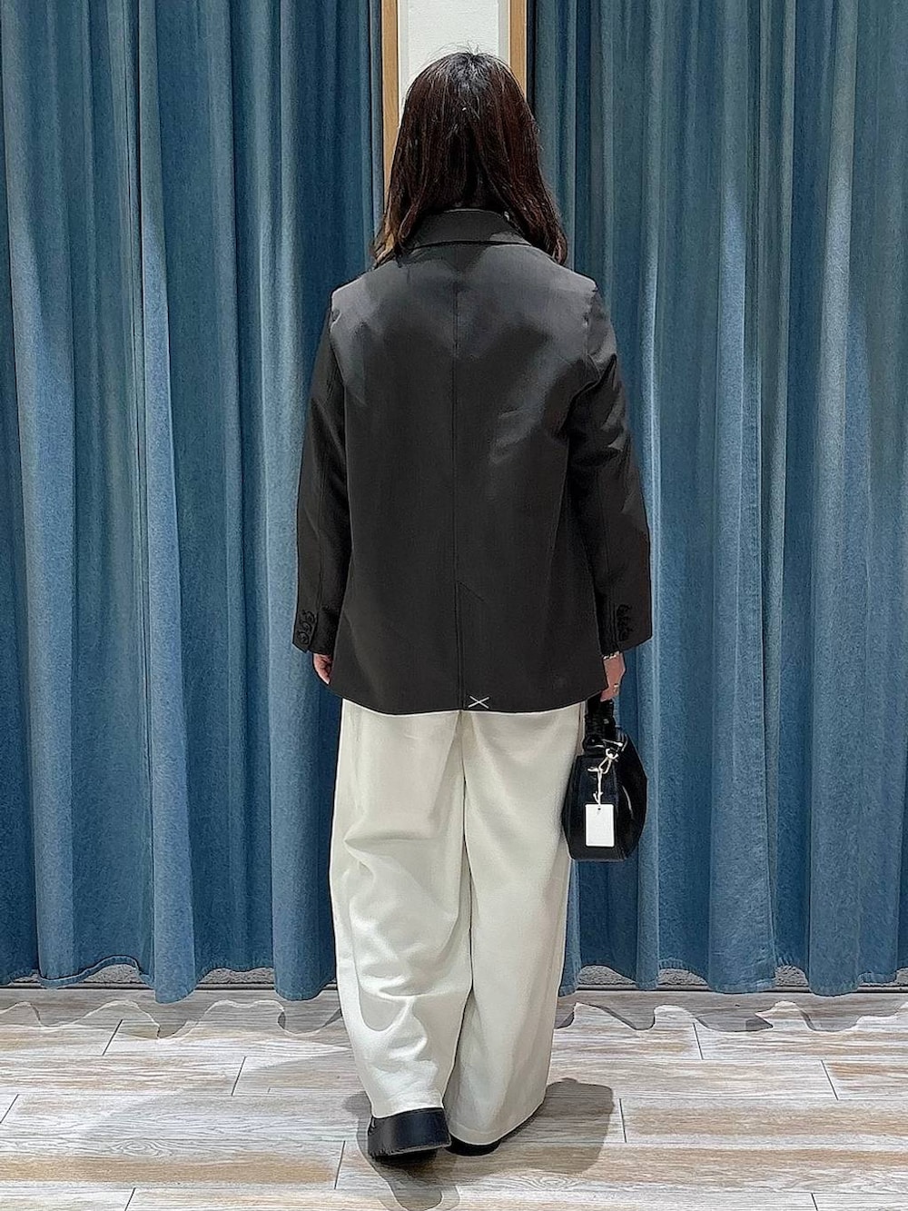 ブラック系のブーツ、ブラック系のハンドバッグ、グレー系のテーラードジャケットを着用したレディースの春コーディネートの3枚目の写真