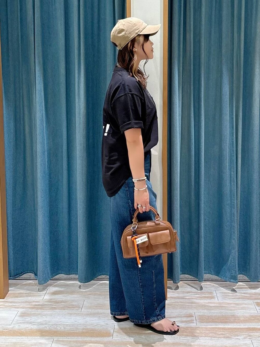 ブルー系のデニムパンツ、ブラック系のTシャツ/カットソー、ブラック系のサンダルを着用したレディースの夏コーディネートの3枚目の写真