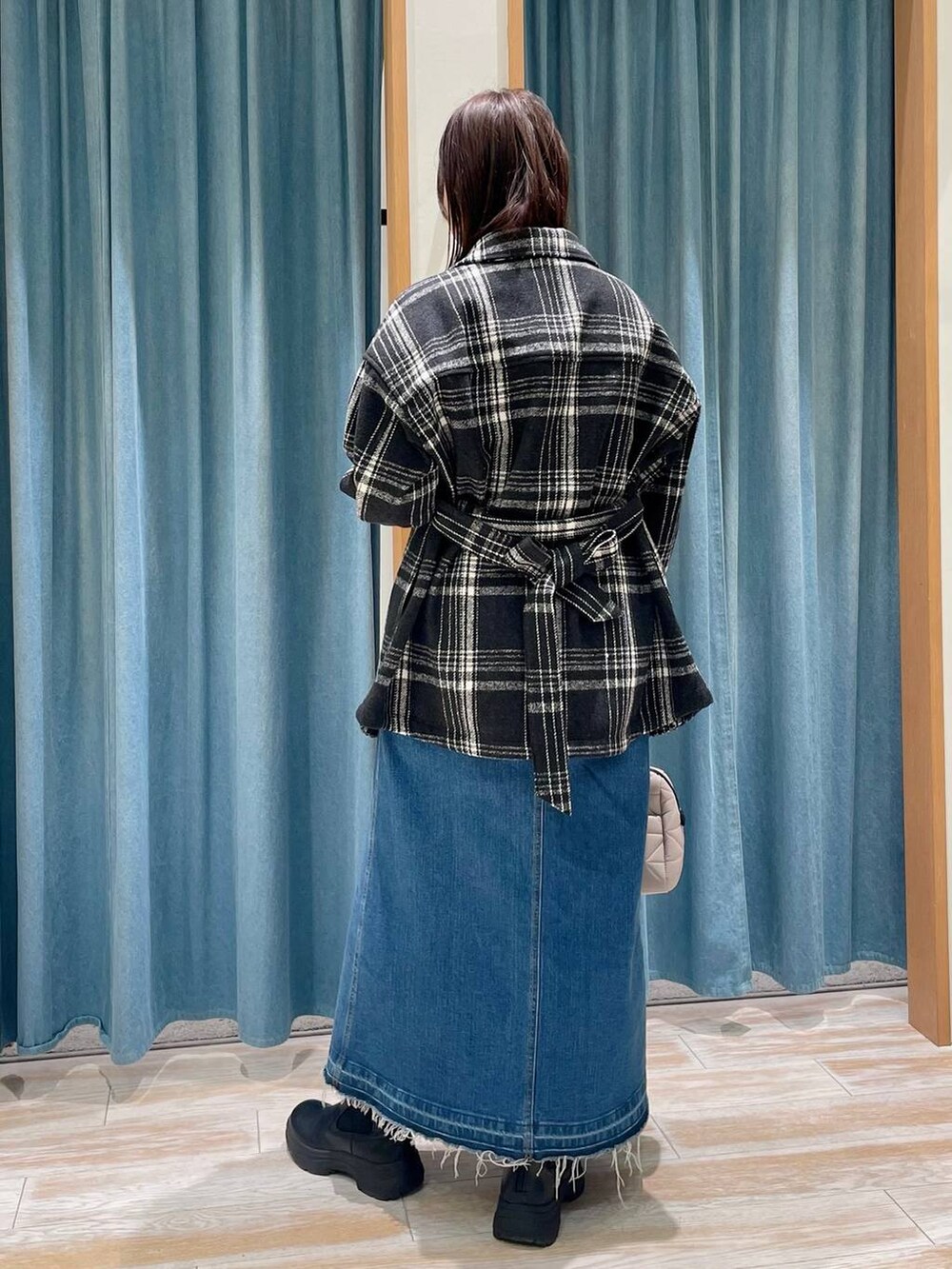 ブルー系のデニムスカート、レッド系のニット/セーター、ブラック系のブーツを着用したレディースの冬コーディネートの3枚目の写真