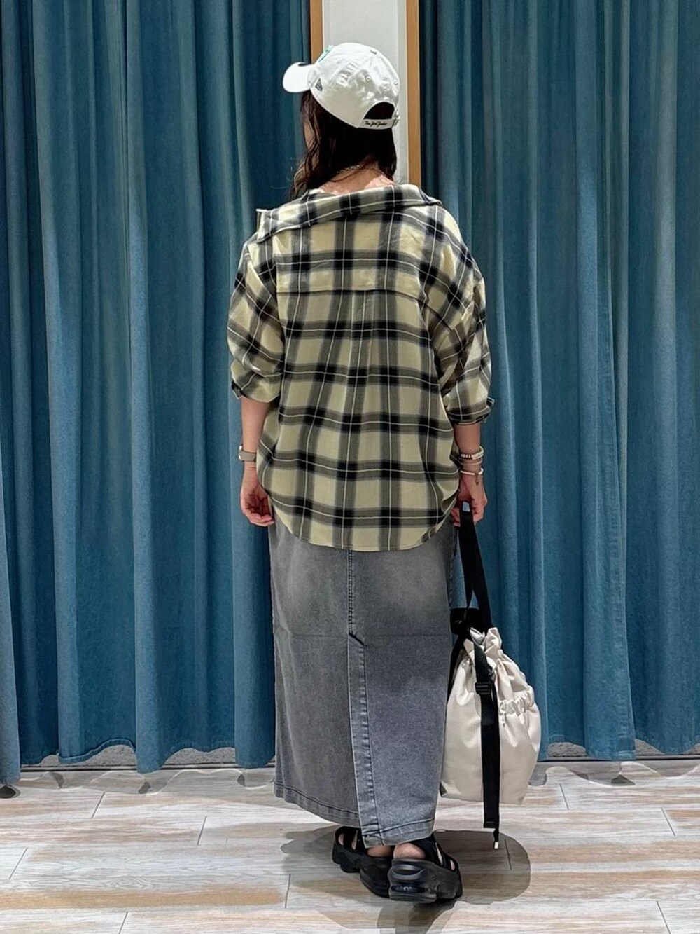 ホワイト系のキャミソール、ホワイト系のトートバッグ、ブラック系のジャンパースカートを着用したレディースの夏コーディネートの3枚目の写真