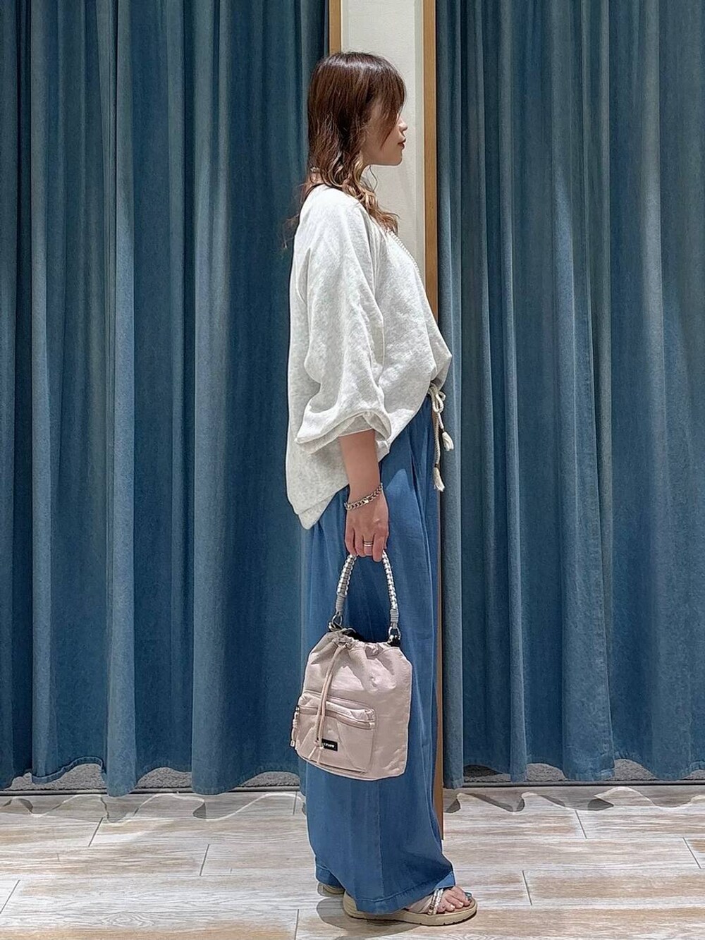 ブルー系のデニムパンツ、グレー系のスウェット、シルバー系のサンダルを着用したレディースの春コーディネートの2枚目の写真