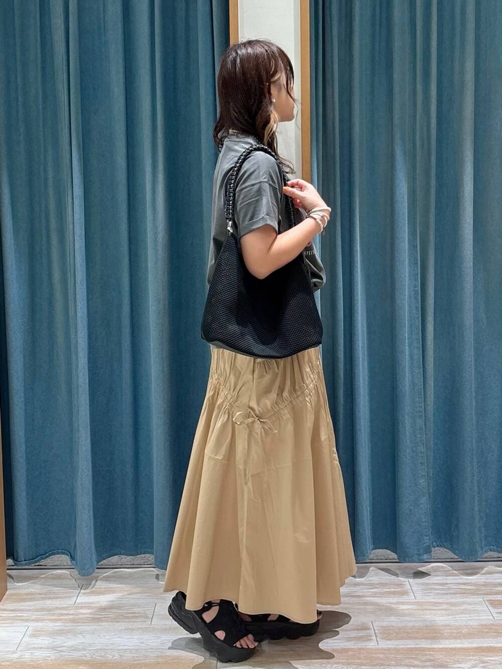 グレー系のTシャツ/カットソー、ブラック系のハンドバッグ、イエロー系のスカートを着用したレディースの夏コーディネートの2枚目の写真