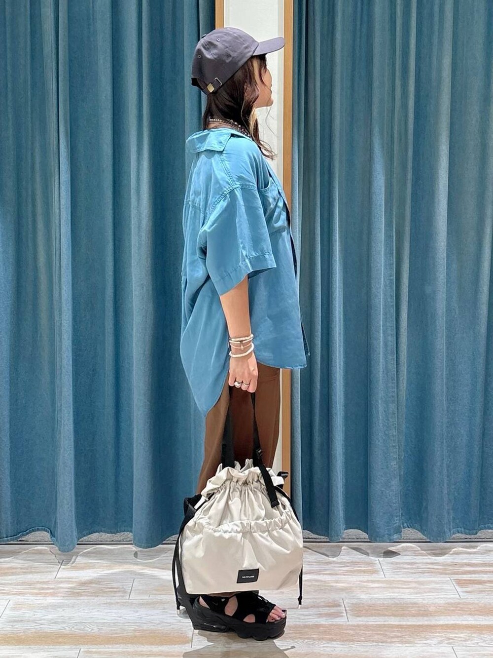 ホワイト系のキャミソール、ホワイト系のトートバッグ、ブルー系のシャツ/ブラウスを着用したレディースの夏コーディネートの2枚目の写真