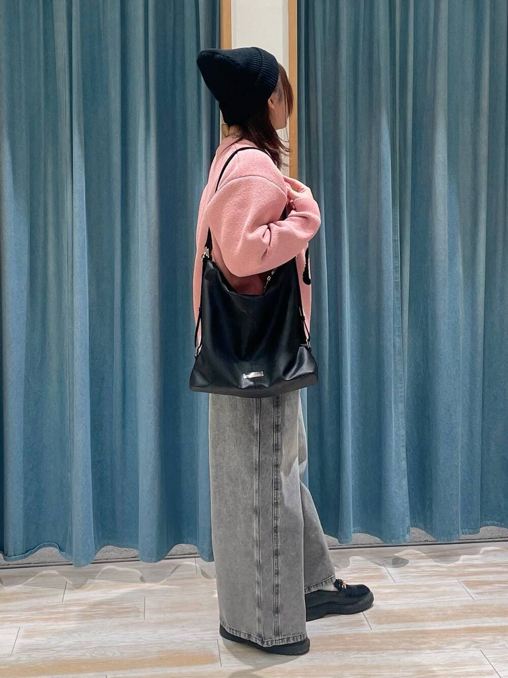 ピンク系のニット/セーター、ブラック系のショルダーバッグ、グレー系のデニムパンツを着用したレディースの冬コーディネートの2枚目の写真